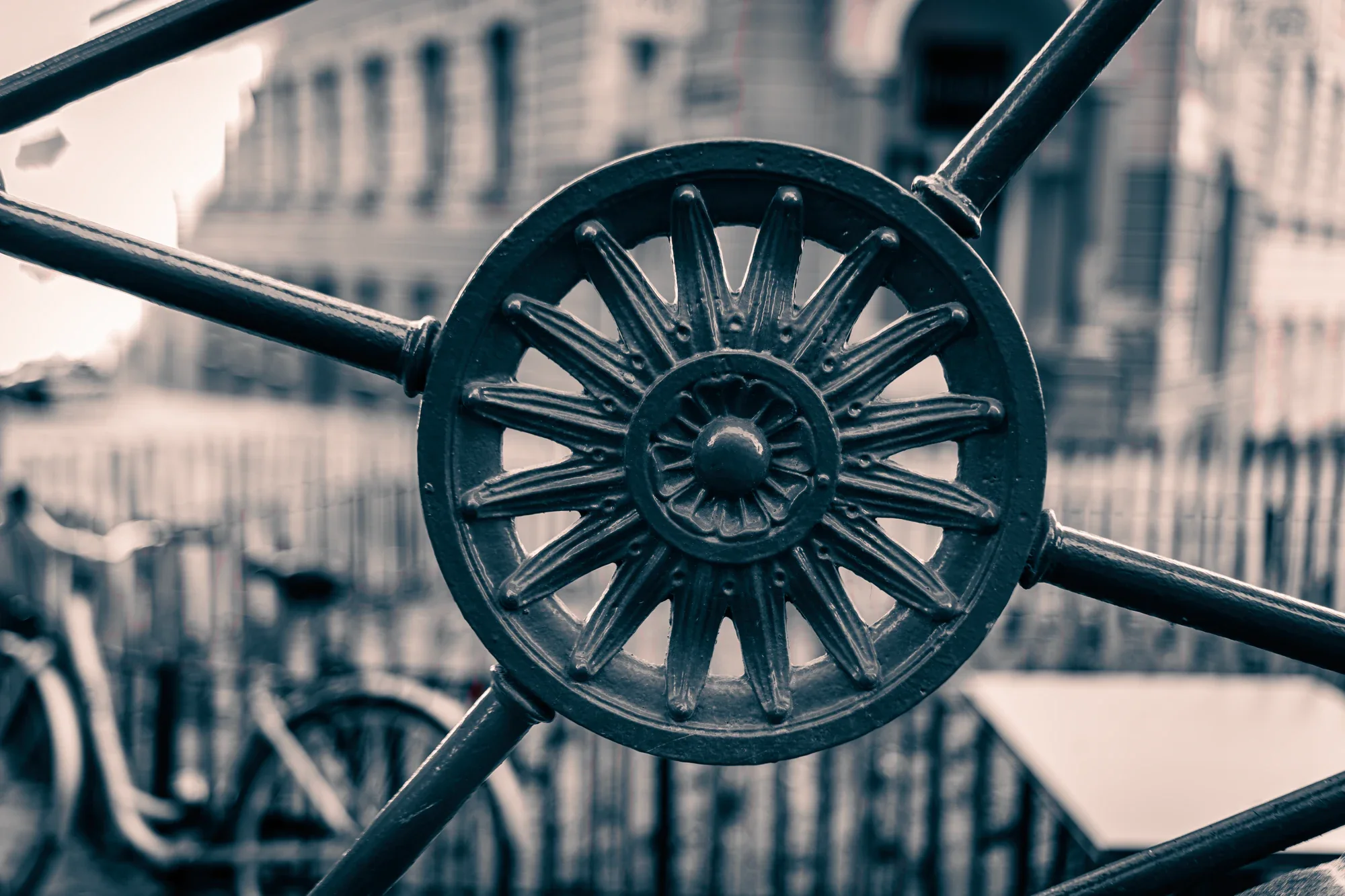 Close view of a radial iron rosette and curving rails with pale Vienna architecture blurred behind them.